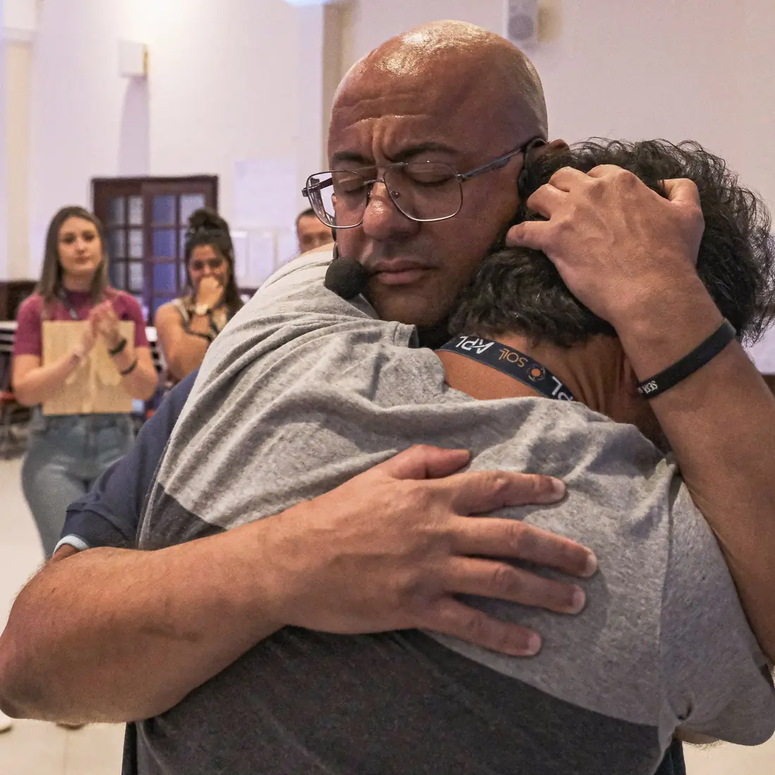 Sóstenes abraça um participante emocionado enquanto colegas aplaudem ao fundo