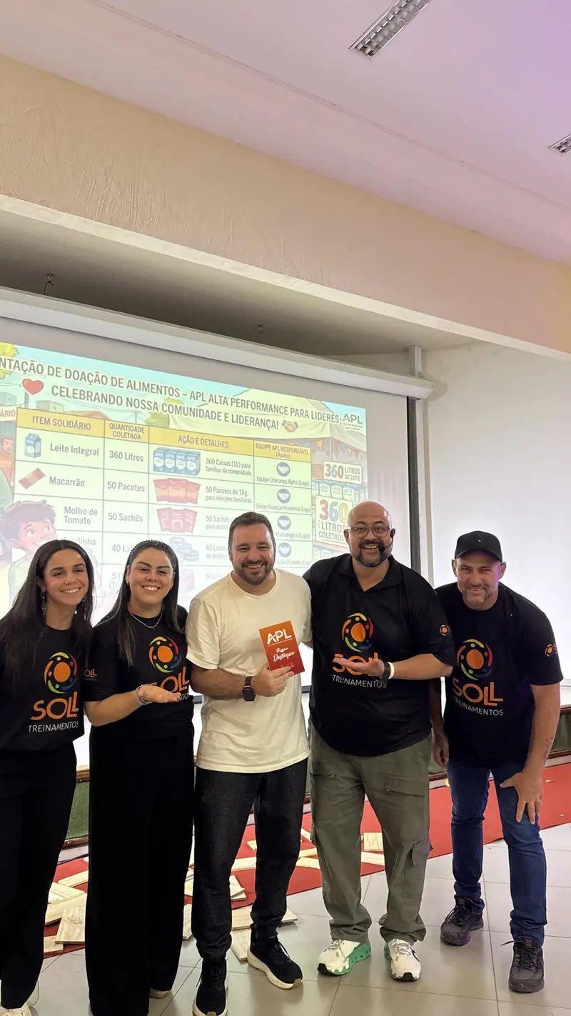 Equipe Soll com um participante destaque diante do telão com o resultado da campanha de doação de alimentos