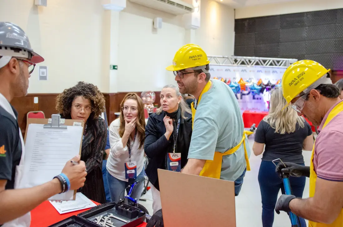 Equipe com capacetes e aventais discutindo com um auditor que segura uma prancheta