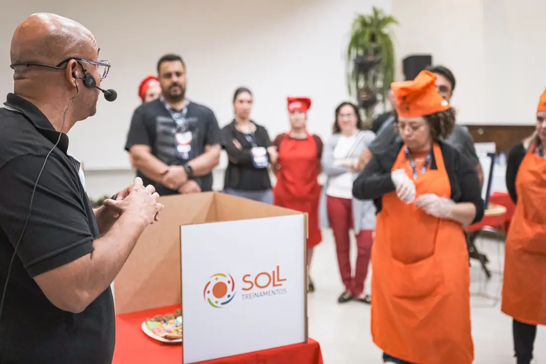 Sóstenes observa participantes de avental durante uma dinâmica